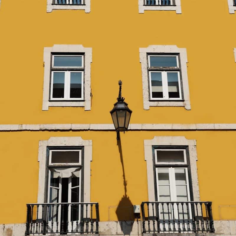 Yellow building facade with multiple white windows and a decorative lantern, relevant to discussions on real estate and property aesthetics in Florida.