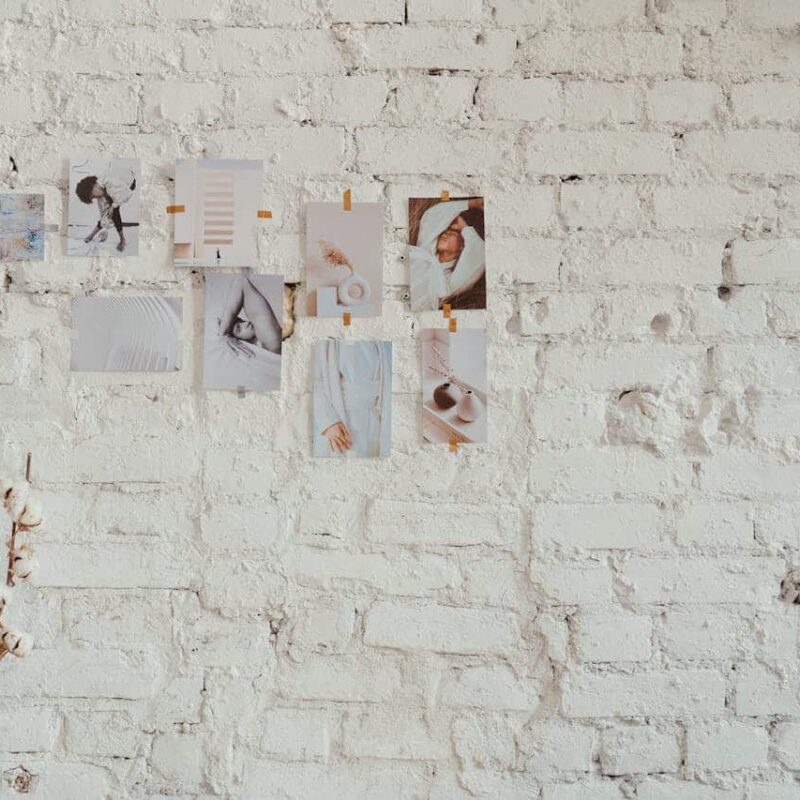 Images of aesthetic photographs pinned to a white brick wall, showcasing a minimalist design related to home decor and lifestyle themes.