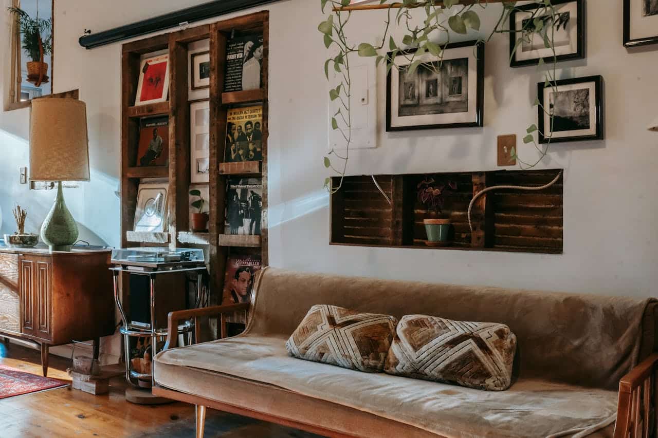 Cozy living room interior featuring a vintage sofa with patterned cushions, a wooden record shelf displaying vinyl records, and a stylish lamp, emphasizing a welcoming atmosphere.